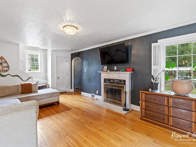 living room featuring hardwood / wood-style floors, a high end fireplace, a healthy amount of sunlight, and ornamental molding