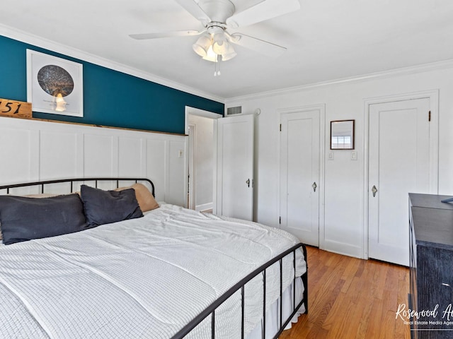 bedroom featuring light wood-type flooring, ceiling fan, and ornamental molding