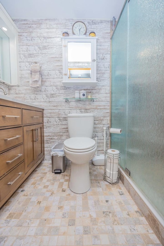 bathroom featuring vanity, toilet, an enclosed shower, and wood walls