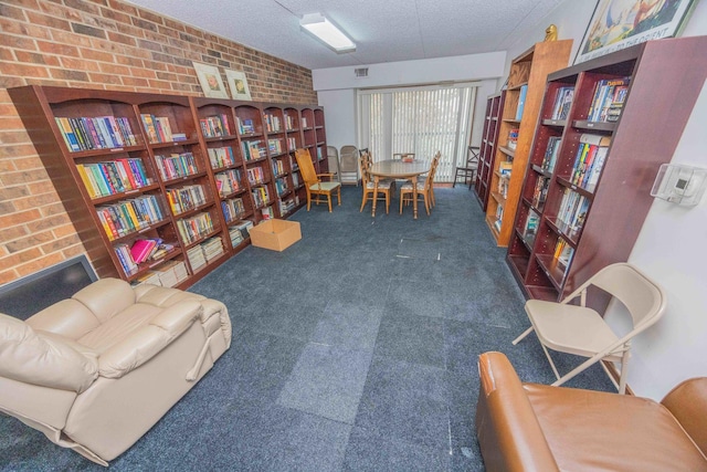 living area featuring dark carpet, a textured ceiling, and brick wall