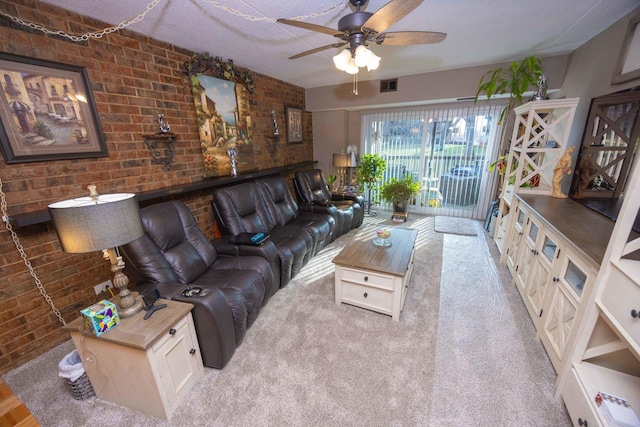 carpeted living room with ceiling fan, brick wall, and a textured ceiling