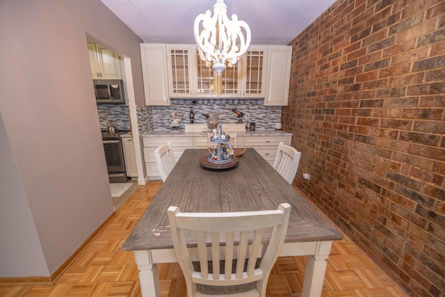 kitchen with white cabinetry, stainless steel appliances, backsplash, pendant lighting, and light parquet flooring