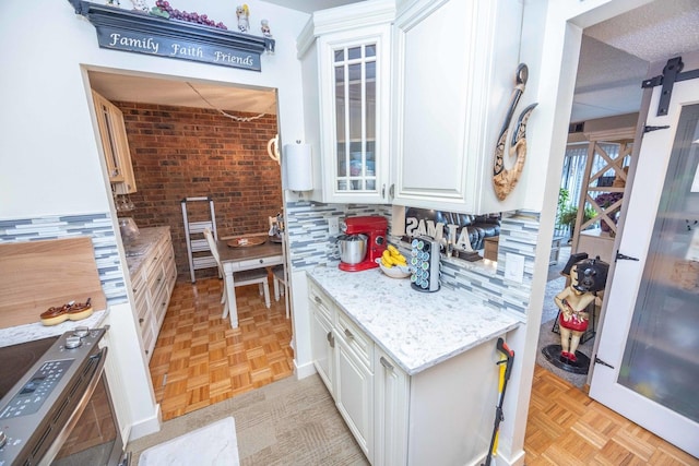 kitchen featuring light parquet floors, white cabinets, tasteful backsplash, light stone counters, and brick wall