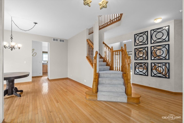 stairway with wood-type flooring and an inviting chandelier