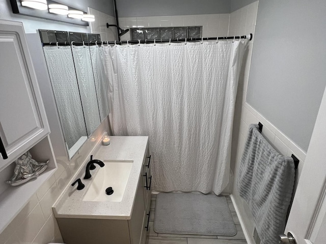 bathroom with a shower with curtain, vanity, and tile walls