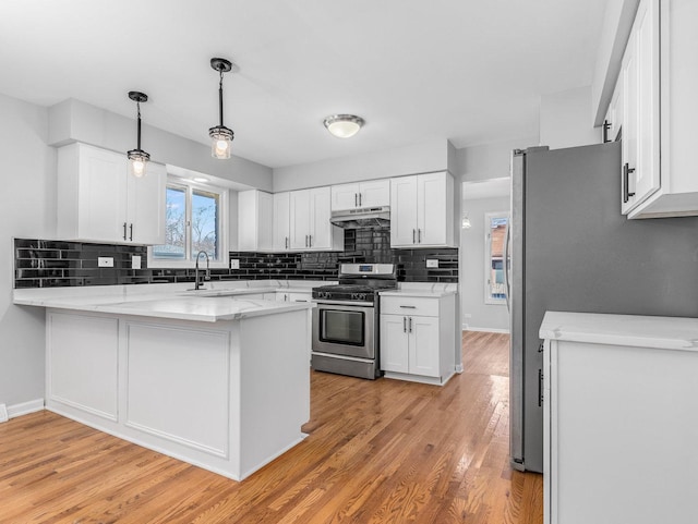 kitchen featuring white cabinets, kitchen peninsula, stainless steel appliances, and hanging light fixtures