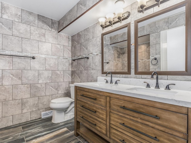 bathroom featuring vanity, toilet, and tile walls