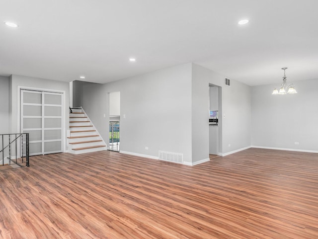 spare room with light hardwood / wood-style floors and a notable chandelier