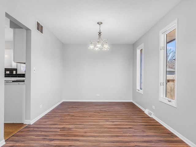 unfurnished dining area with a notable chandelier and dark hardwood / wood-style floors