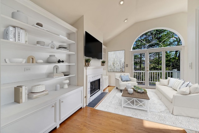 living room with vaulted ceiling, built in features, and light wood-type flooring