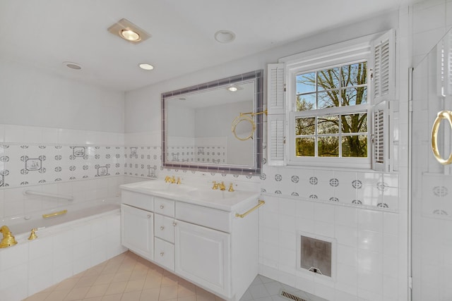 bathroom with tiled bath, tile walls, tile patterned floors, and vanity