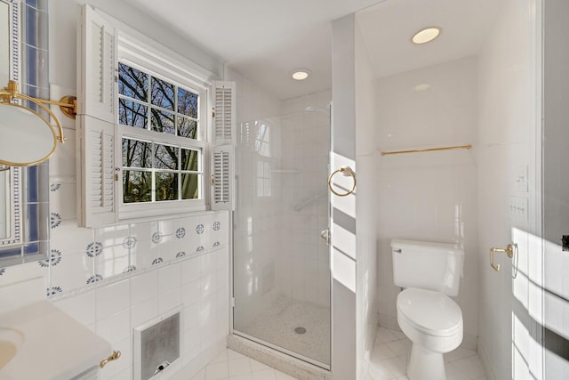 bathroom with tile walls, toilet, and a shower with door