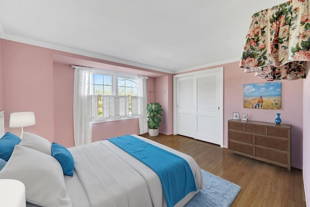 bedroom with a closet, hardwood / wood-style flooring, and crown molding