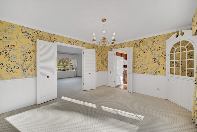 carpeted spare room featuring ornamental molding and a notable chandelier