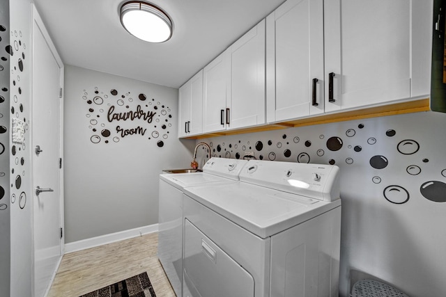 clothes washing area with cabinets, independent washer and dryer, and light hardwood / wood-style flooring