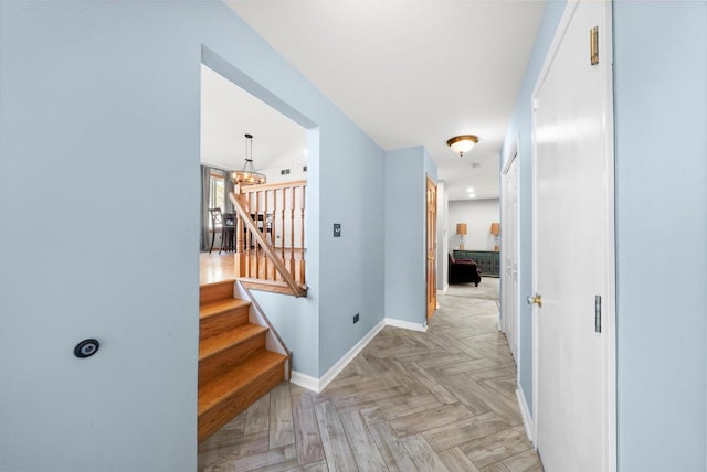 hall featuring light parquet floors and a notable chandelier