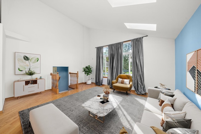 living room with a skylight, high vaulted ceiling, and hardwood / wood-style flooring