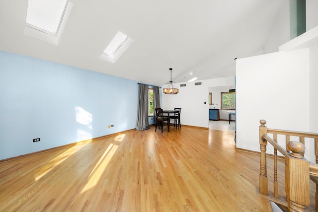 unfurnished living room featuring hardwood / wood-style flooring and vaulted ceiling with skylight