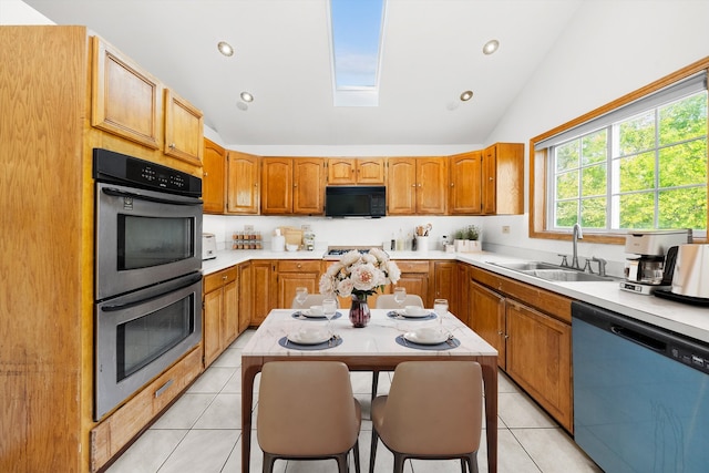 kitchen with lofted ceiling with skylight, sink, light tile patterned floors, and stainless steel appliances