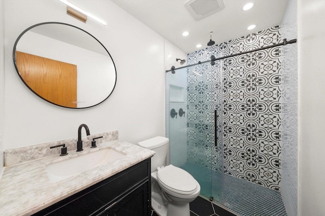 bathroom with a tile shower, vanity, toilet, and tile patterned floors