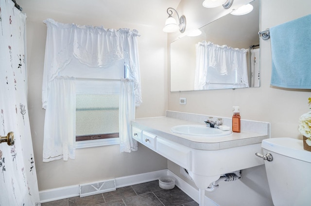 bathroom featuring toilet, sink, and tile patterned flooring