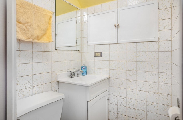 bathroom featuring vanity, toilet, and tile walls