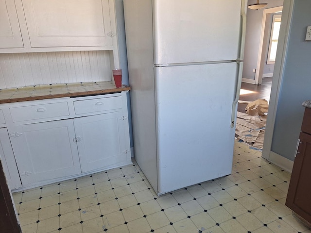 kitchen featuring butcher block countertops, white cabinetry, and white fridge