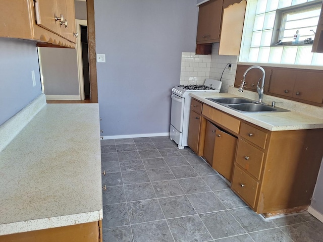 kitchen featuring tasteful backsplash, white gas stove, dark tile patterned flooring, and sink