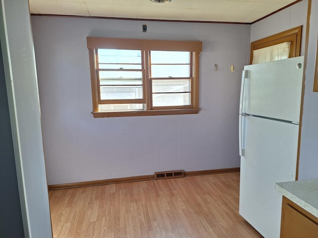 kitchen featuring light hardwood / wood-style flooring, ornamental molding, and white refrigerator