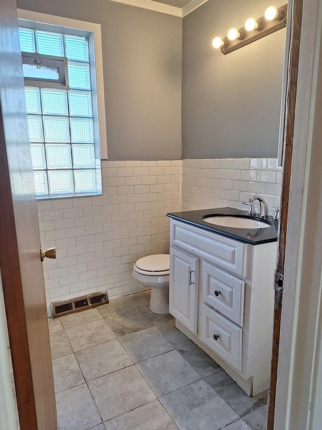 bathroom featuring tile patterned flooring, vanity, toilet, and tile walls