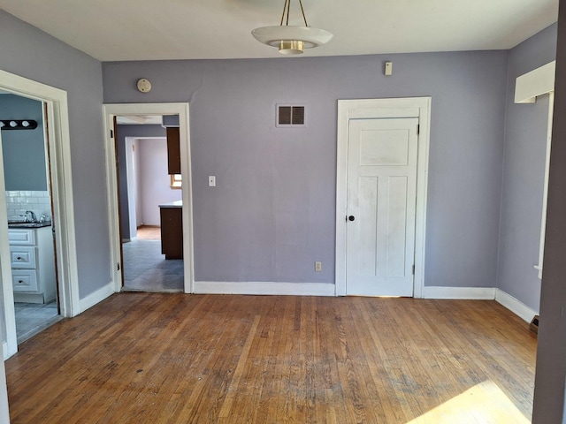 unfurnished room with hardwood / wood-style floors and sink