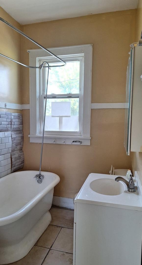 bathroom with tile patterned flooring, vanity, and a tub