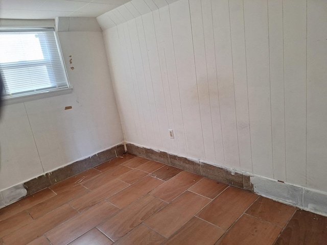 empty room featuring hardwood / wood-style floors, vaulted ceiling, and wood walls