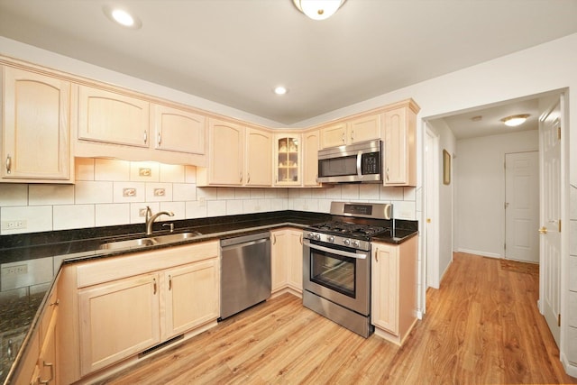 kitchen featuring sink, light brown cabinets, light hardwood / wood-style flooring, backsplash, and appliances with stainless steel finishes