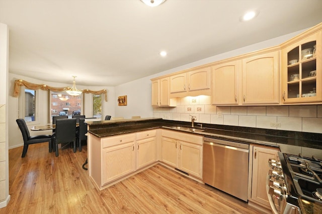 kitchen with kitchen peninsula, light wood-type flooring, backsplash, stainless steel appliances, and pendant lighting