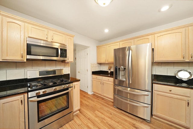 kitchen with decorative backsplash, light wood-type flooring, light brown cabinetry, and appliances with stainless steel finishes