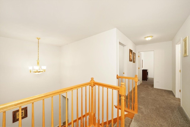 hall featuring dark carpet and a notable chandelier