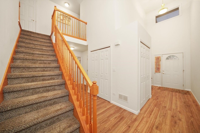 stairway with a high ceiling and hardwood / wood-style flooring