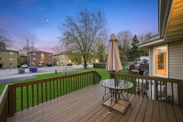 deck at dusk featuring a yard