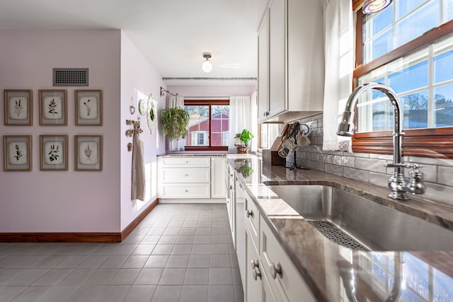 kitchen with white cabinetry, sink, tile patterned flooring, and tasteful backsplash