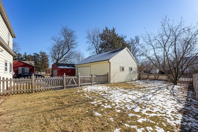 yard layered in snow featuring a garage and an outdoor structure