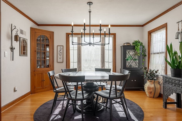 dining area featuring crown molding, a chandelier, and light hardwood / wood-style flooring