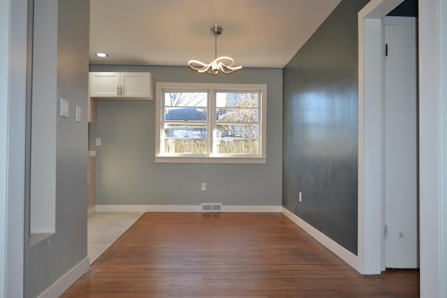 unfurnished dining area featuring hardwood / wood-style flooring and a notable chandelier