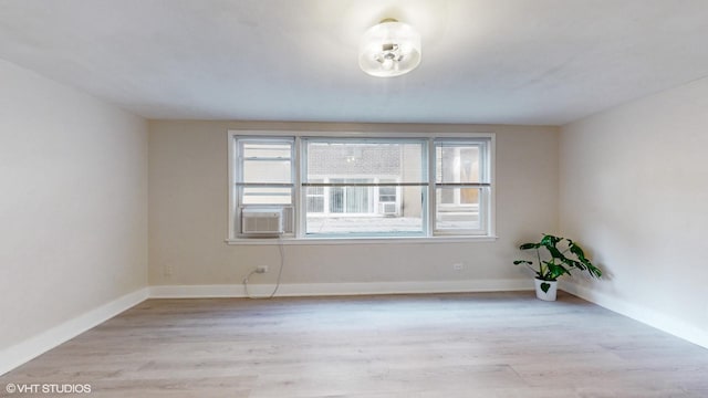 spare room with plenty of natural light, cooling unit, and light wood-type flooring