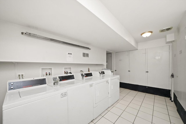 laundry area with washing machine and clothes dryer and light tile patterned floors