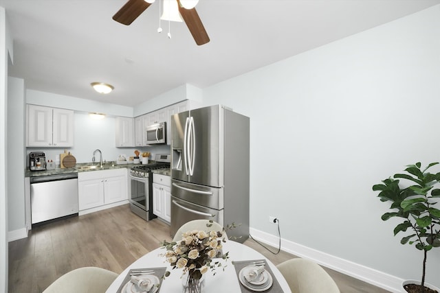 kitchen featuring sink, ceiling fan, appliances with stainless steel finishes, light hardwood / wood-style floors, and white cabinetry