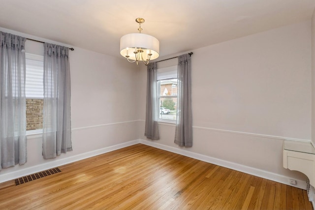 empty room with a notable chandelier and wood-type flooring