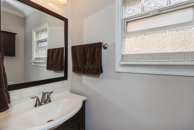 bathroom featuring vanity, crown molding, and tasteful backsplash