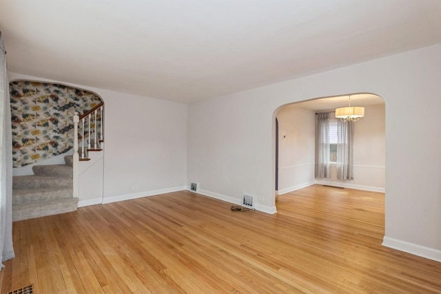 empty room featuring hardwood / wood-style flooring and a notable chandelier