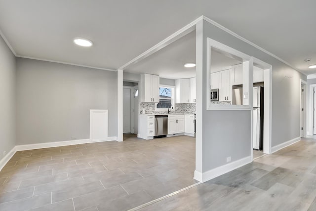 kitchen with backsplash, crown molding, sink, white cabinetry, and stainless steel appliances